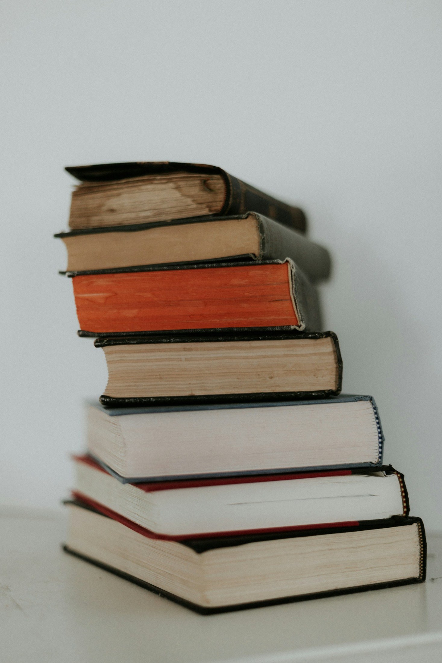Pila de libros de distintos colores con cubiertas y lomos desgastados.