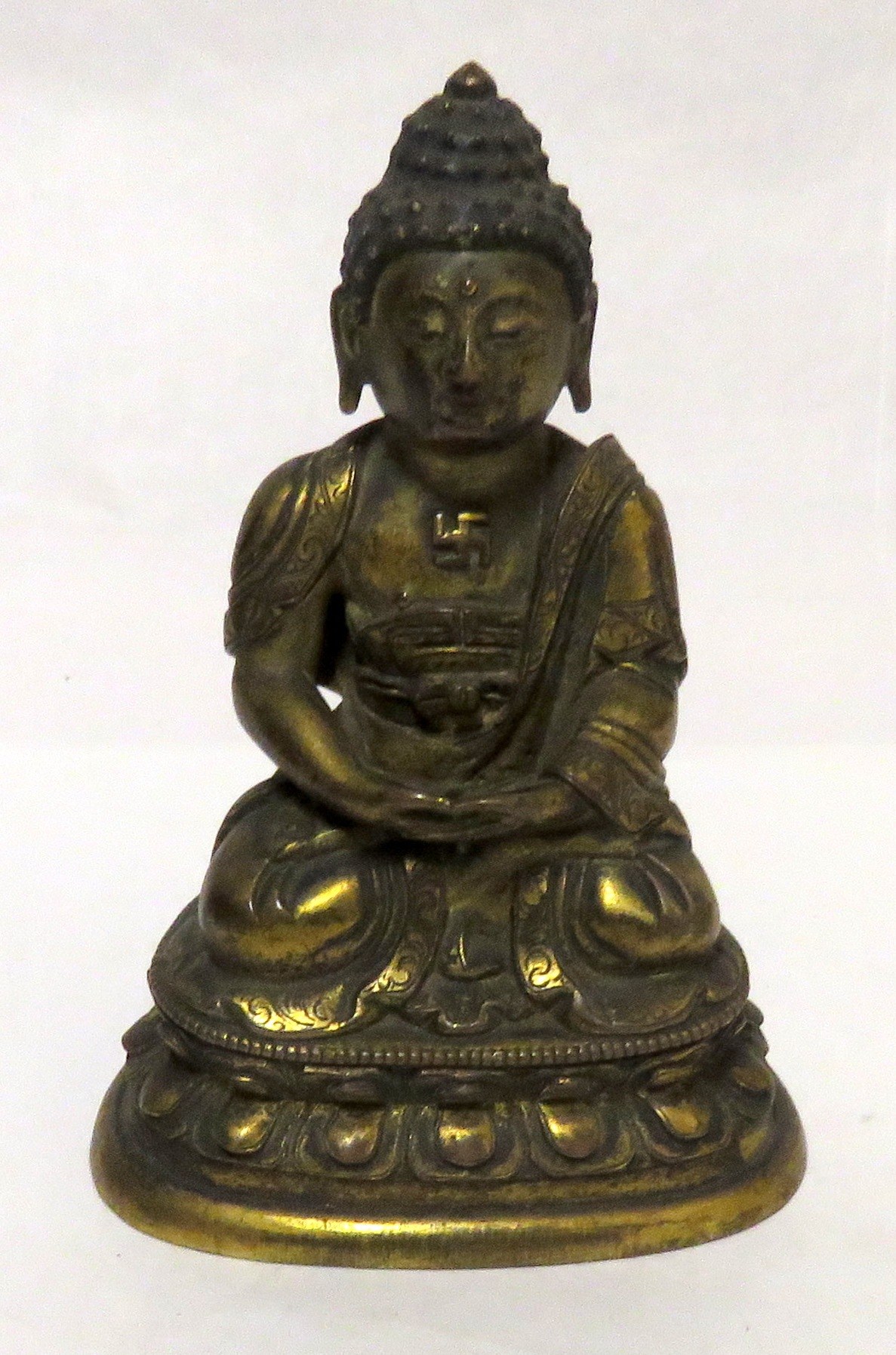 Figura de Buda de metal dorado, con una esvástica visible en el pecho.